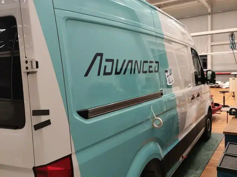 Advanced Bikes van with turquoise vehicle graphics in the workshop